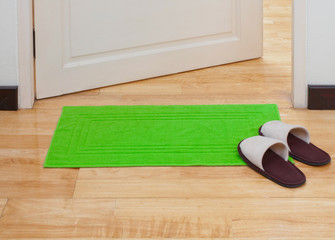 Green doormat with house slippers