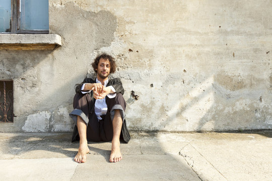 portrait man sitting on the floor against a wall