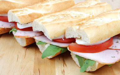 three fresh sandwiches with tomato , ham and mozzarella