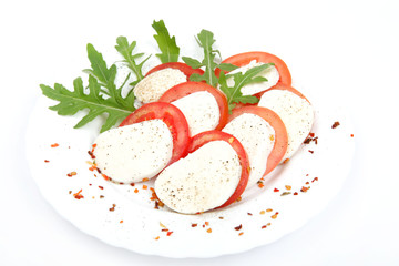 Tomato and mozzarella with basil leaves on a plate