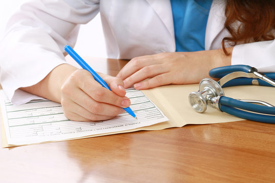 A female doctor is fiiling a prescription - close-up