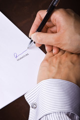 Human hand with pen signing a document