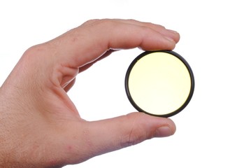 man hand holds a yellow photographic filter, isolated on white