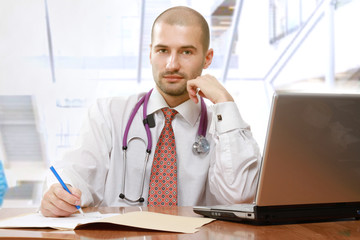 A male doctor at his workplace, isolated on white, side-view