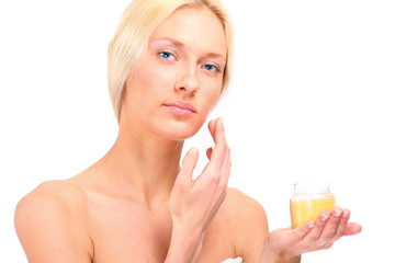A woman applying cream on face, isolated on white
