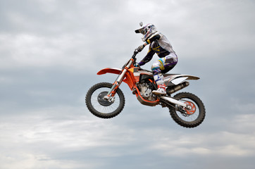motocross rider jumps high against the sky