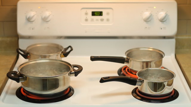 Four pots full of boiling water on the electric stove.