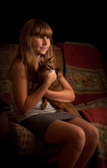 Girl with cat, indoors. Low key.