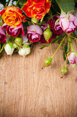 Fototapeta na wymiar multicolored roses on a wooden board