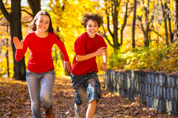 Girl and boy running, jumping in park