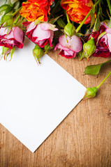 bouquet of roses and white cardboard on a wooden board
