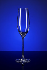 leeres sektglas auf einem schwarzen spiegel mit blauem licht