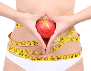 woman's waist with measuring tape holding red apple