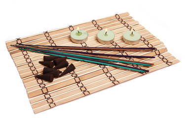 candles, incense cones and sticks on bamboo mat isolated