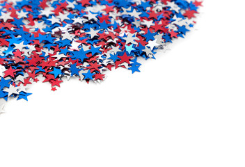 Red white and blue star shaped confetti on a white background