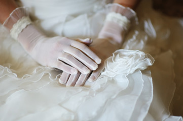 Bride's hands with manicure in white lace gloves