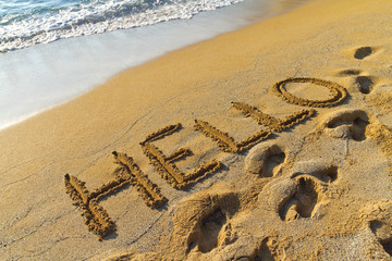 hello greeting written in a golden sandy beach