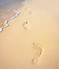 Fototapeta na wymiar Footprints na piaszczystej plaży wzdłuż morza