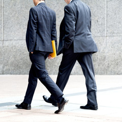 Two businessmen walking on the background of the office.