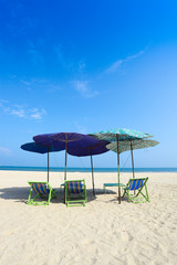 Comfort chairs and umbrella on the beach under the blue sky