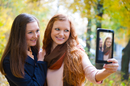 Two girls taking picture with digital tablet