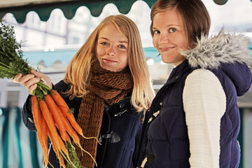 two young women buying carrots