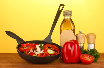 frying pan with vegetables on yellow background