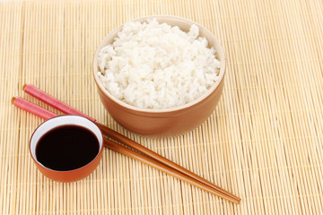 Bowl of rice and chopsticks on bamboo mat