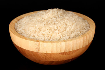 White polished rice in wooden bowl isolated on black