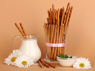 Tasty crispy sticks in glass cup on beige background