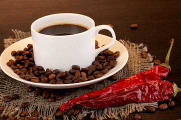 Coffee and pepper on wooden table on brown background