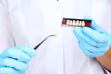 Dental tweezers and denture in dentists hands