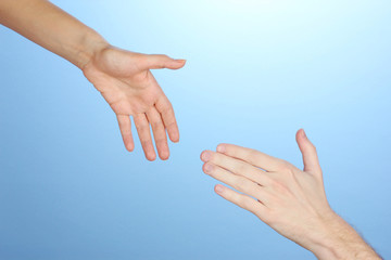 Women's hand goes to the man's hand on blue background