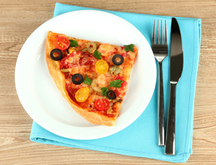 plate with a slice of delicious pizza on wooden background