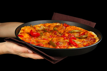 hands holding pepperoni pizza in pan isolated on black