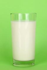 Glass of fresh new milk on green background