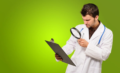 Young Doctor Holding Magnifying Glass And Clipboard