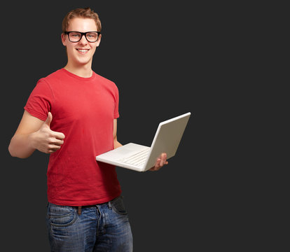 Man holding laptop with thumbs up