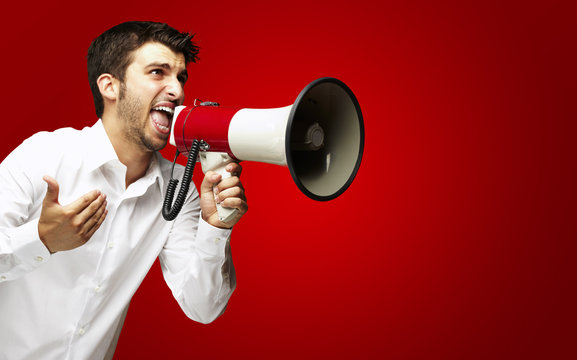 portrait of young man shouting with megaphone over red backgroun