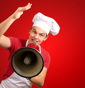 portrait of happy cook man shouting using megaphone over red bac