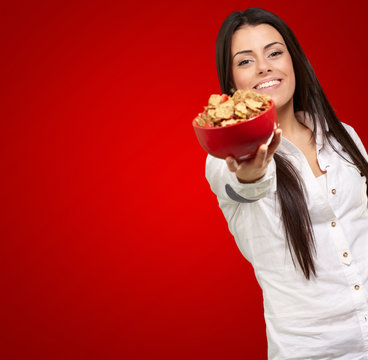 portrait of young woman offering cereals bowl over red backgroun