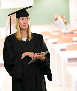 Confused Graduate Woman Holding Digital Tablet