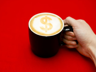 hand grabbing coffee cup with dollar sign