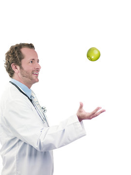 happy doctor tossing green apple in air