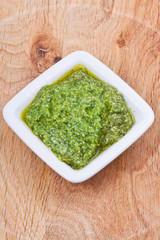 saucer with fresh pesto on wooden board