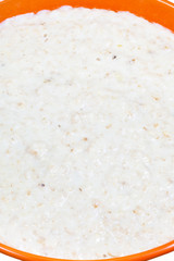 oat porridge with milk in orange bowl close up