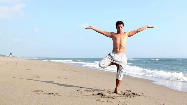 Peaceful fit man practicing yoga on beach