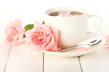 cup of tea with roses on white wooden table