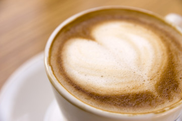 A cup of cappuccino with foam in shape of heart. Shallow DOF