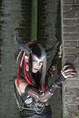 Naklejka premium Scary female demon in front of old dirty brick wall.